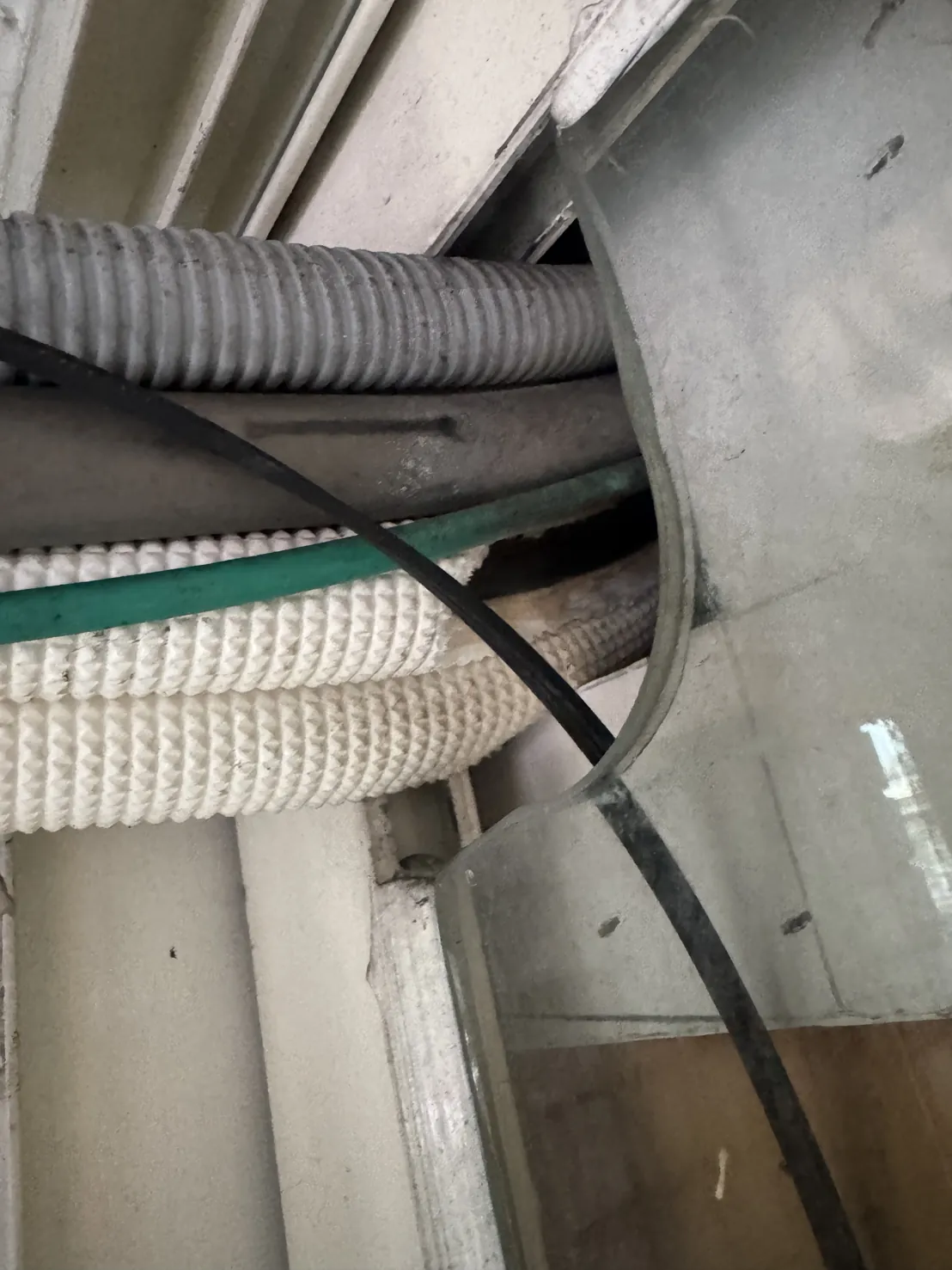 冷氣管、排水管與電線從窗框旁的開口穿出，管子周圍留有縫隙