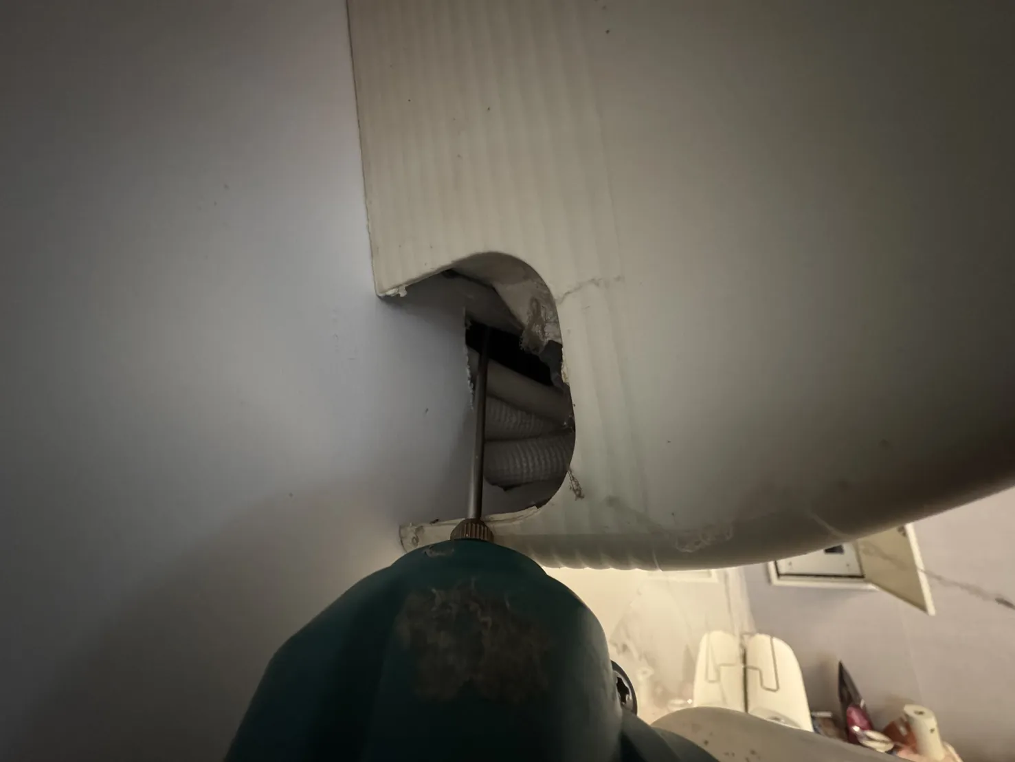 冷氣室內機下方管線穿牆的位置，技師檢查孔洞周圍的縫隙