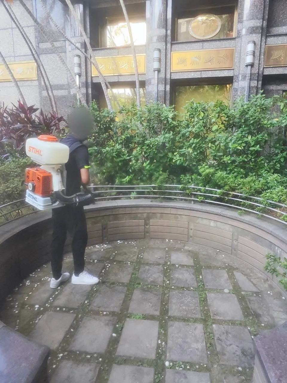 技師在弧形花台內側處理植栽與花台邊緣（臉部已模糊）