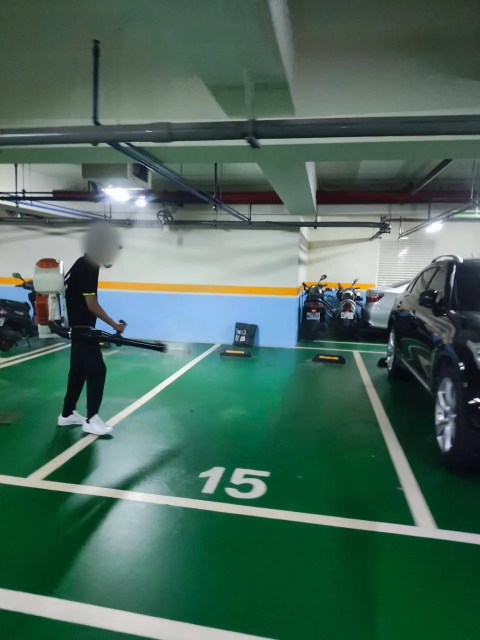 技師處理地下停車場車位地面與擋車塊周邊（臉部已模糊）