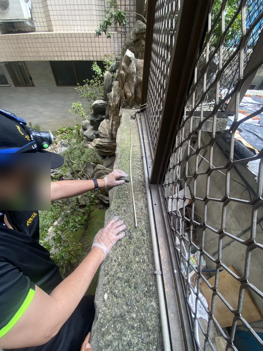 技師沿鐵網與造景交界處塗抹忌避劑，臉部已模糊