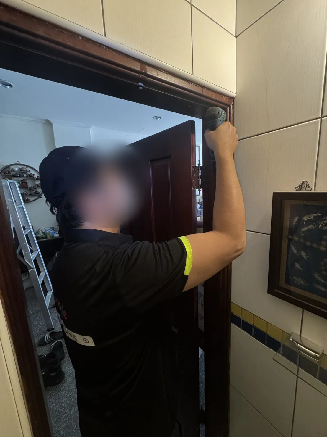 技師從門框上緣開始施作（臉部已模糊）