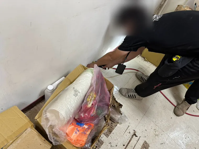 技師搬開紙箱檢查地面（臉部已模糊）