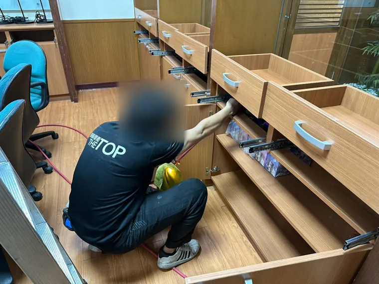 技師拉出整排抽屜對櫃體內部施藥（臉部已模糊）