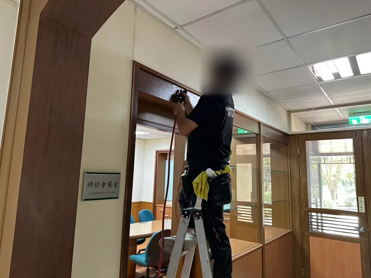 技師沿門框上緣鑽孔（臉部已模糊）