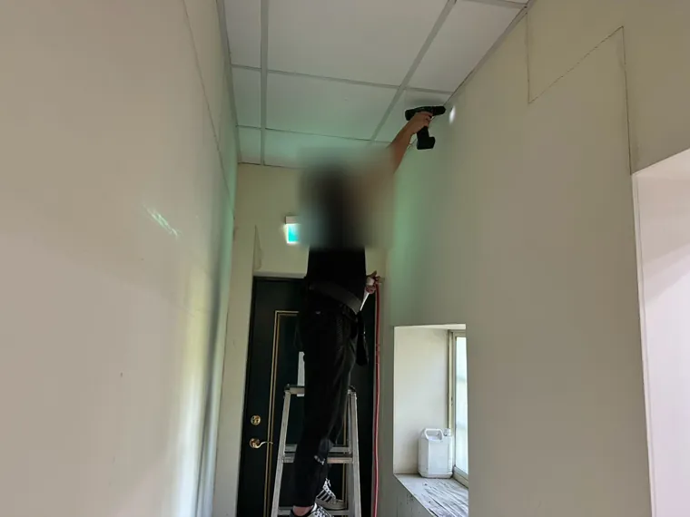 技師處理走廊盡頭的門框（臉部已模糊）