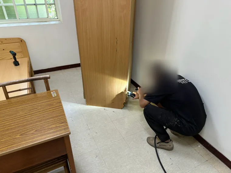 技師在高櫃底部鑽孔注藥（臉部已模糊）