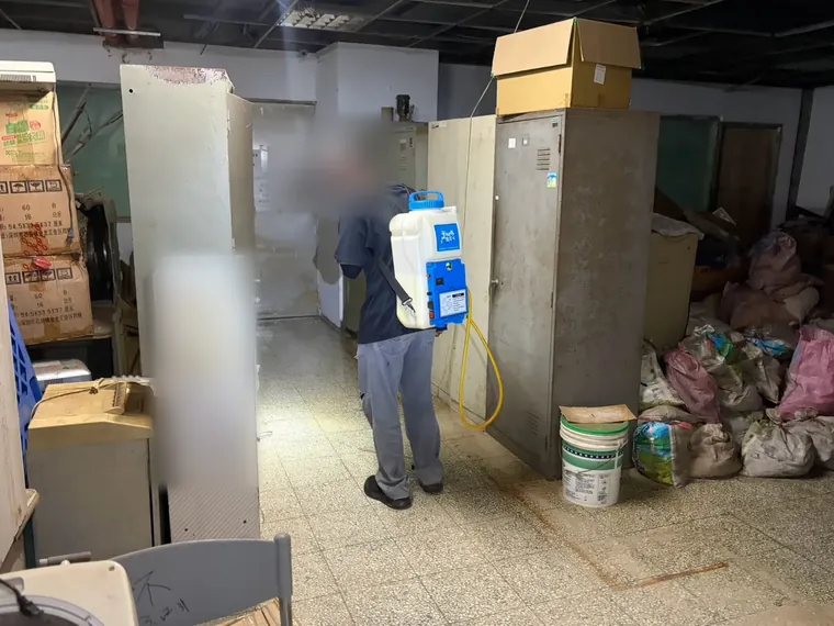 鐵櫃與紙箱之間走道以電動噴霧器噴灑