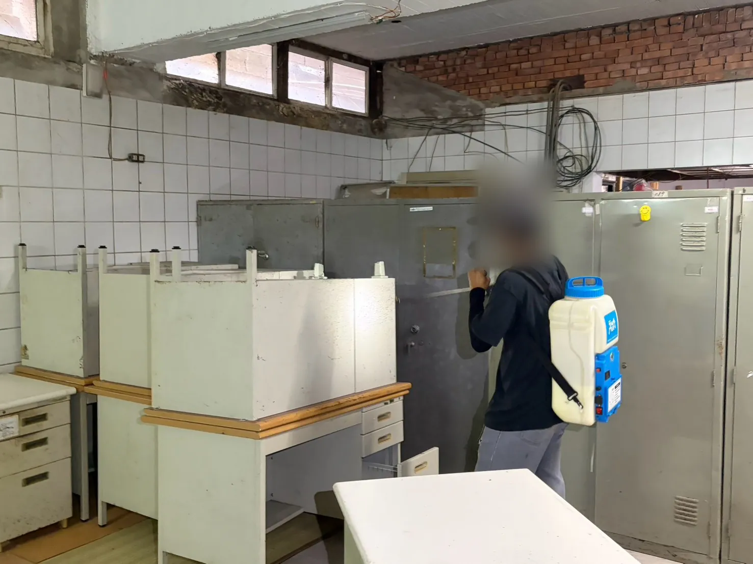 舊廚房不鏽鋼櫃旁技師以噴霧器噴灑