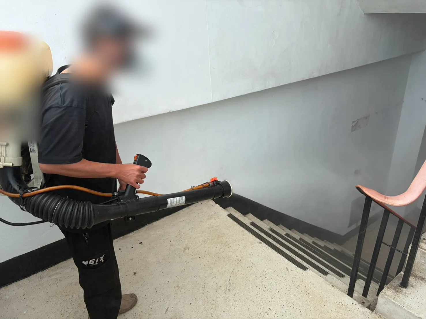 樓梯轉角處技師以動力噴霧機往下霧化