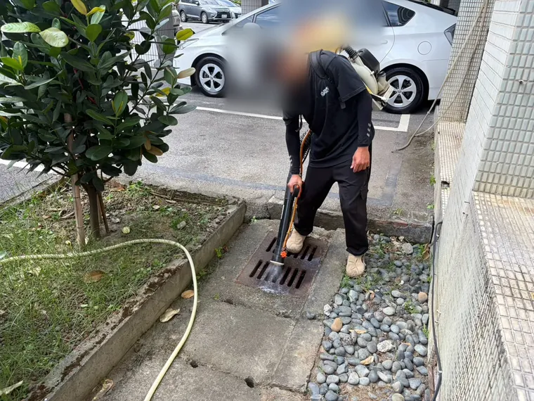 停車場旁水溝蓋以噴霧機對準溝內噴灑