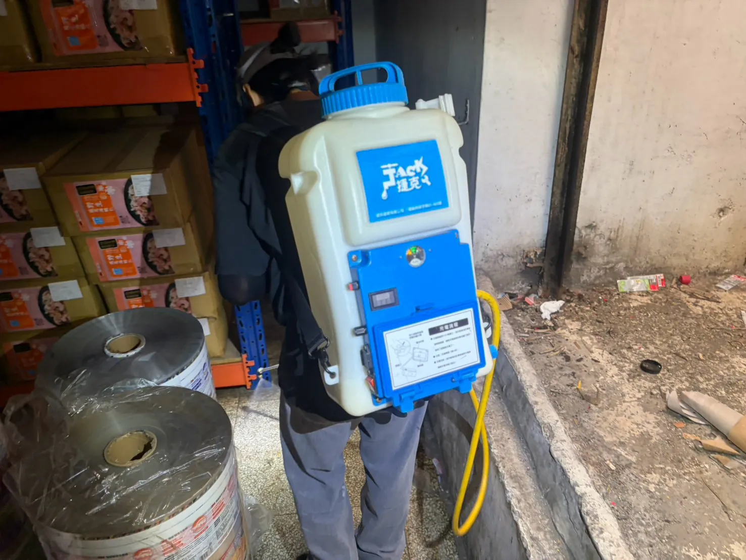 技師背電動噴霧機在倉庫施作