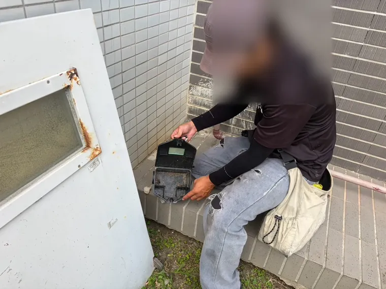 技師在側門邊牆角打開鼠餌盒