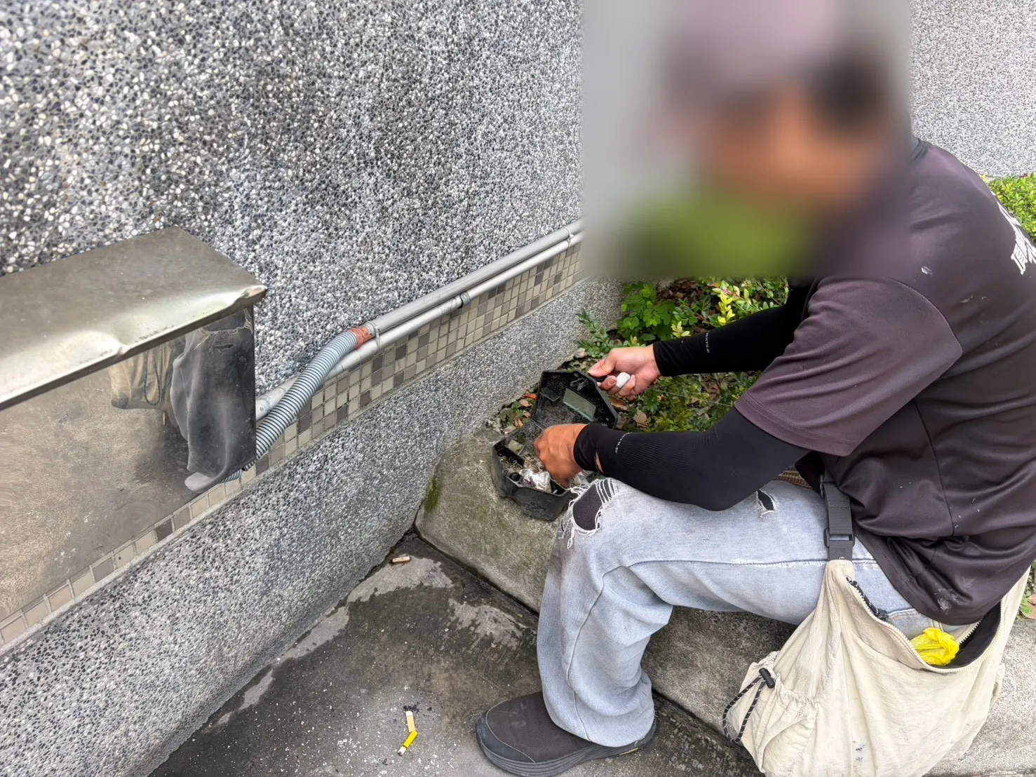 技師在外牆花台旁打開鼠餌盒