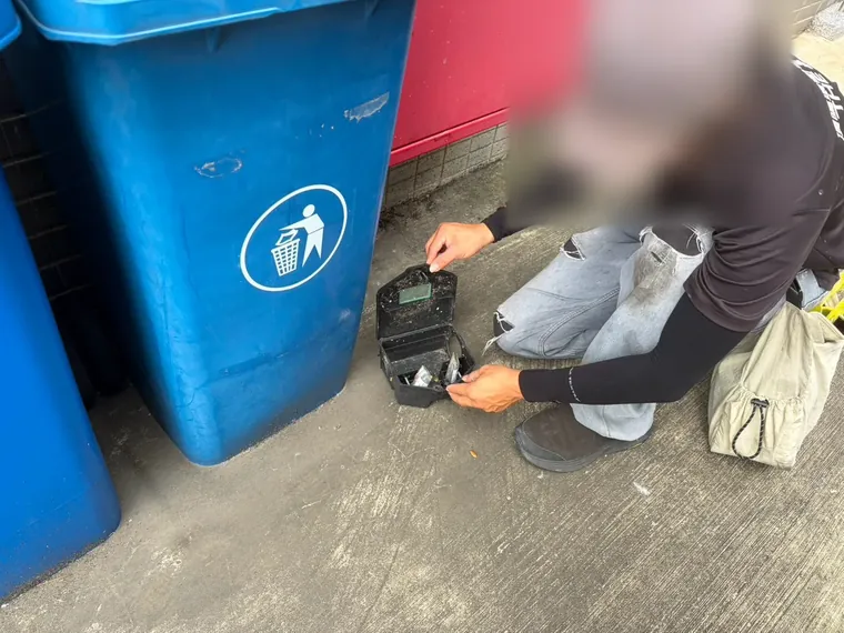 技師在垃圾桶旁打開鼠餌盒檢查