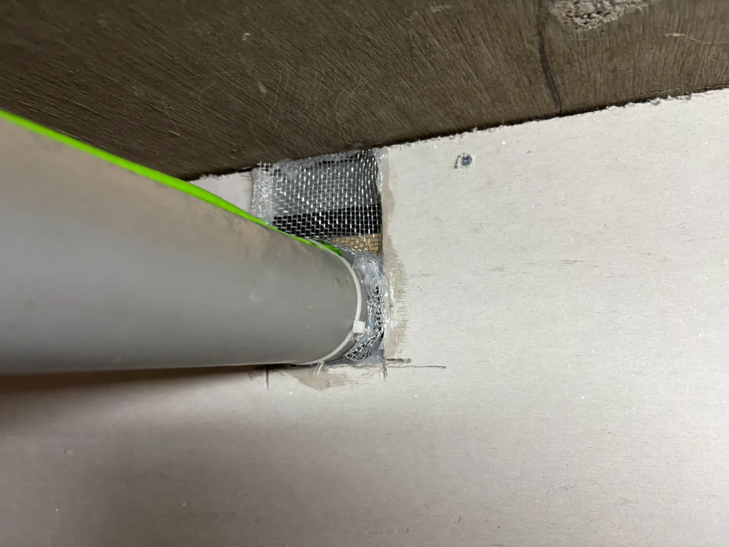 灰色排水管穿過隔間板方洞以防鼠網封住
