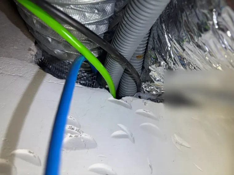 電線水管與風管擠在同一穿牆洞，縫隙以防鼠網塞住