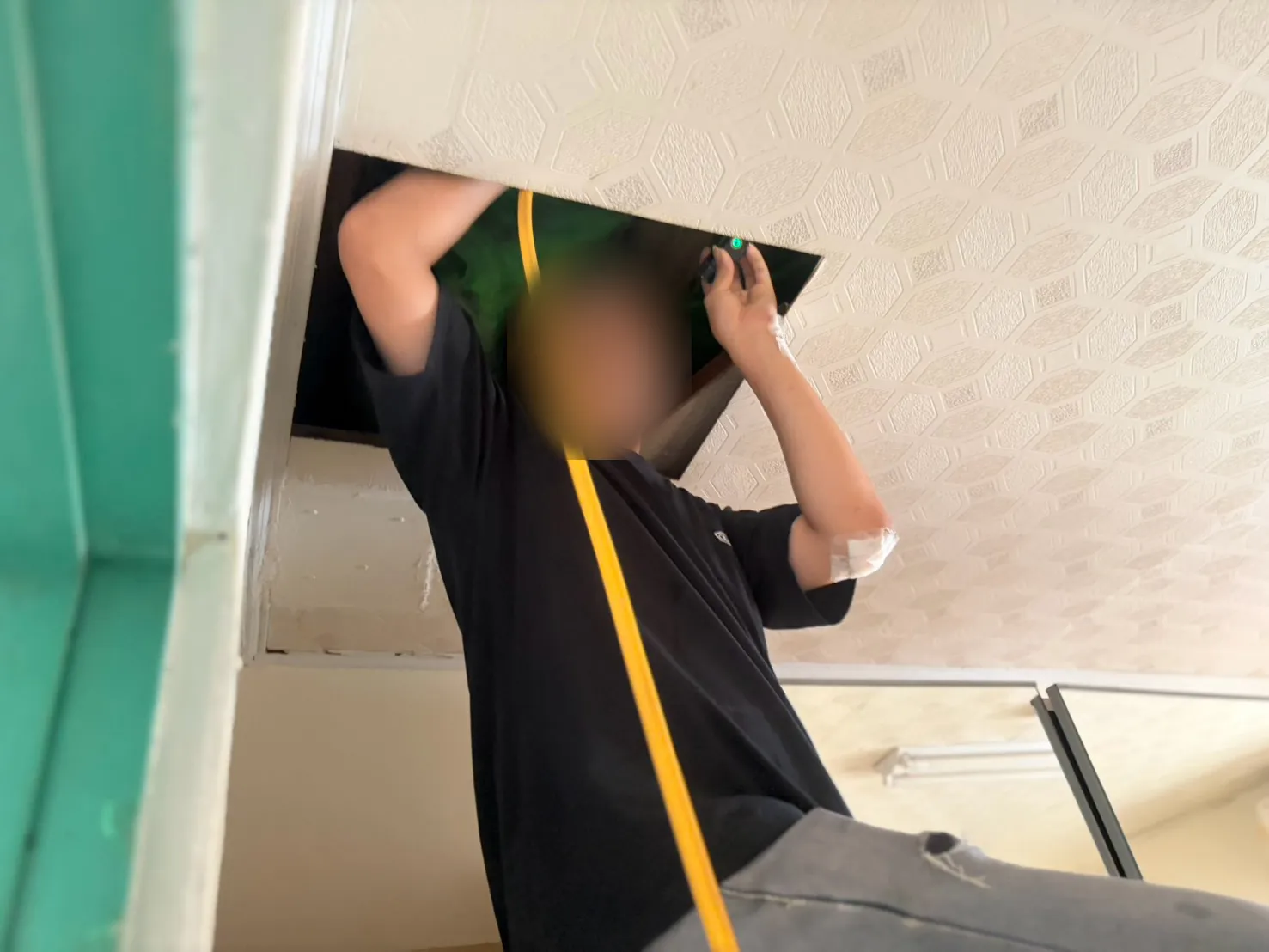 技師打開天花板檢修孔，帶著藥管與手電筒進入屋頂夾層（臉部已模糊）
