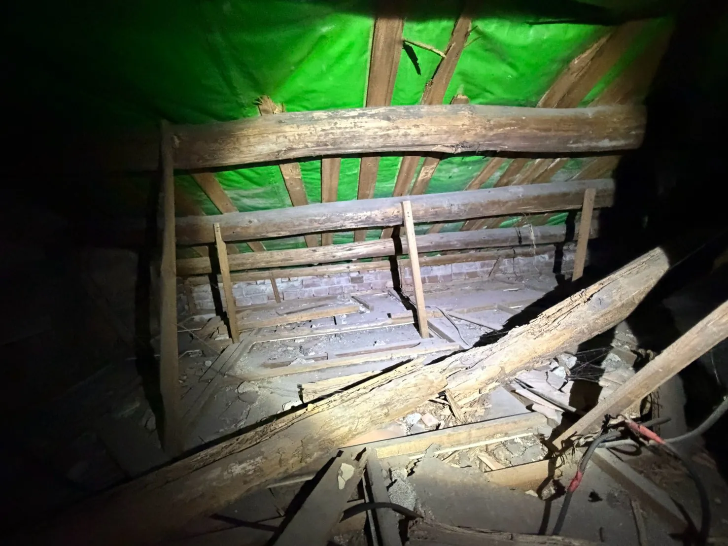 老屋屋頂夾層內被白蟻蛀蝕的木樑，表面坑洞層層剝落