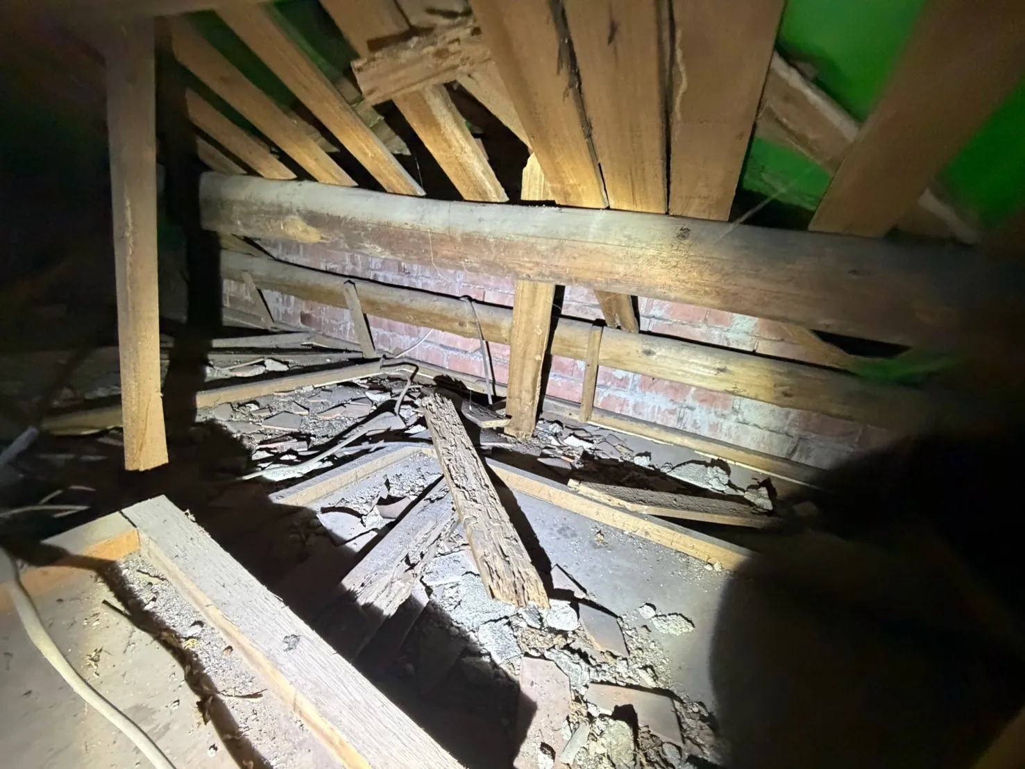 屋頂夾層內斷裂倒下的木料，天花板背面滿是碎屑與土塊