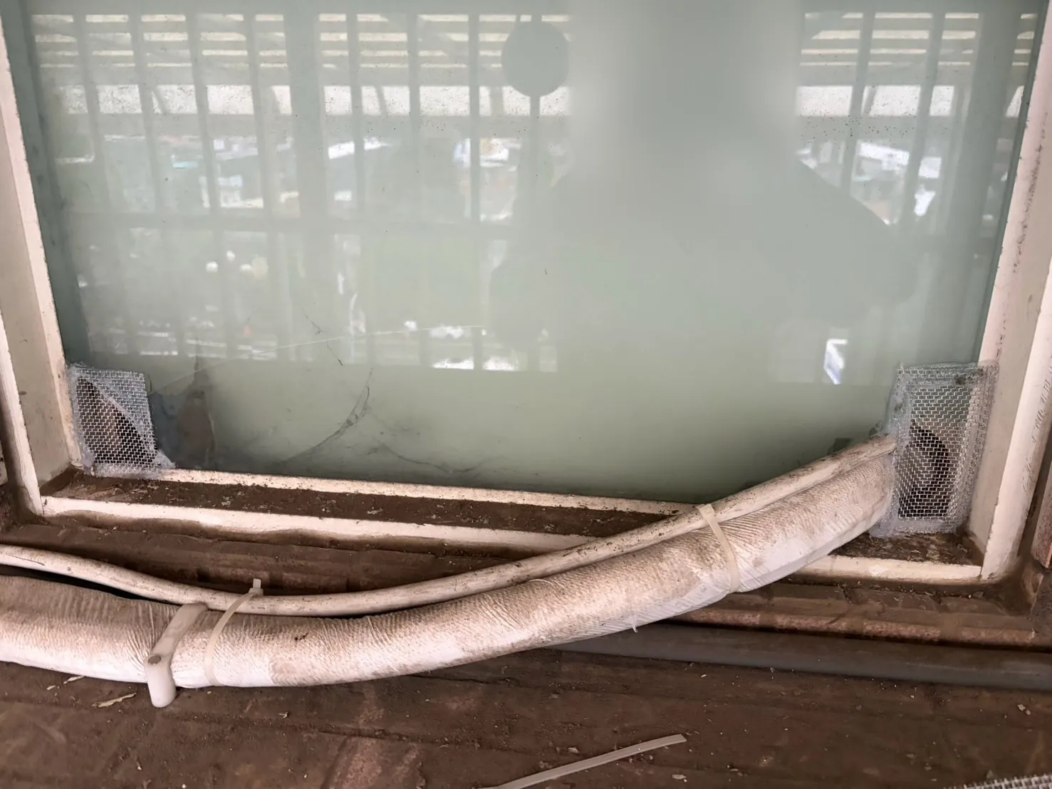 冷氣管線經過的窗框下緣兩側缺口以不鏽鋼防鼠網封堵