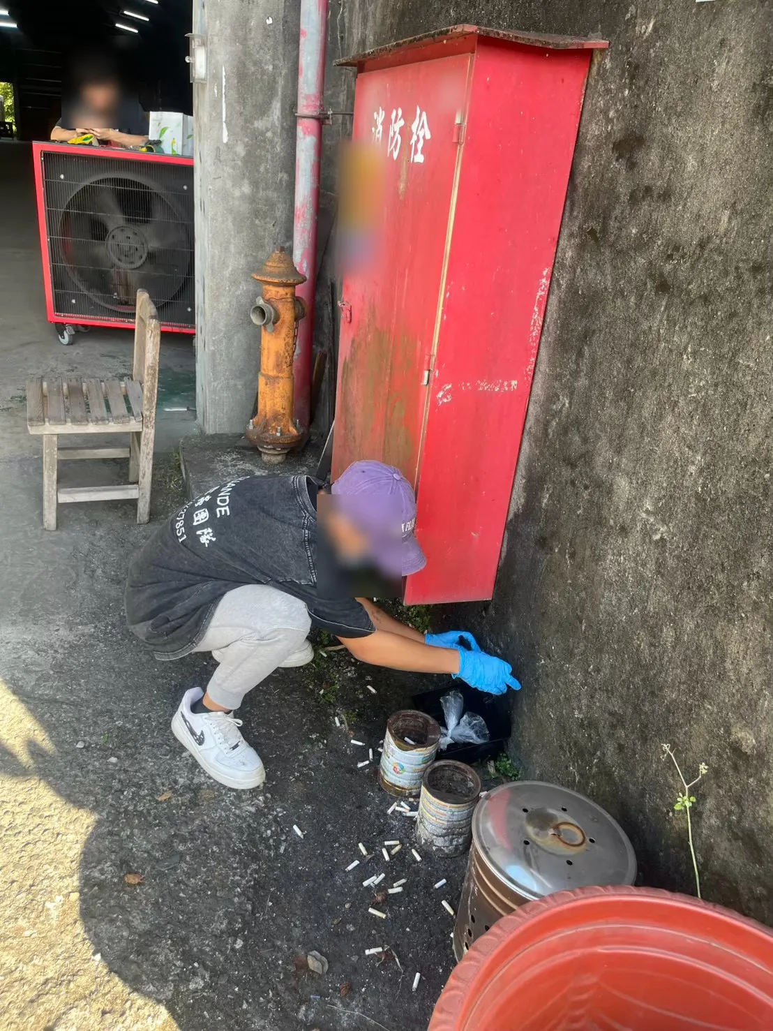 業者在工廠消防栓箱下方牆腳打開鼠餌盒換餌