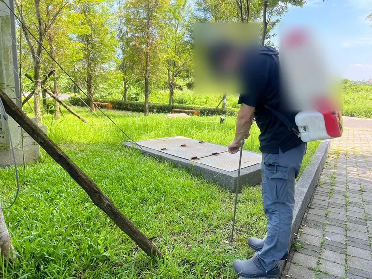 草地中人孔蓋周圍以電動噴霧器噴灑
