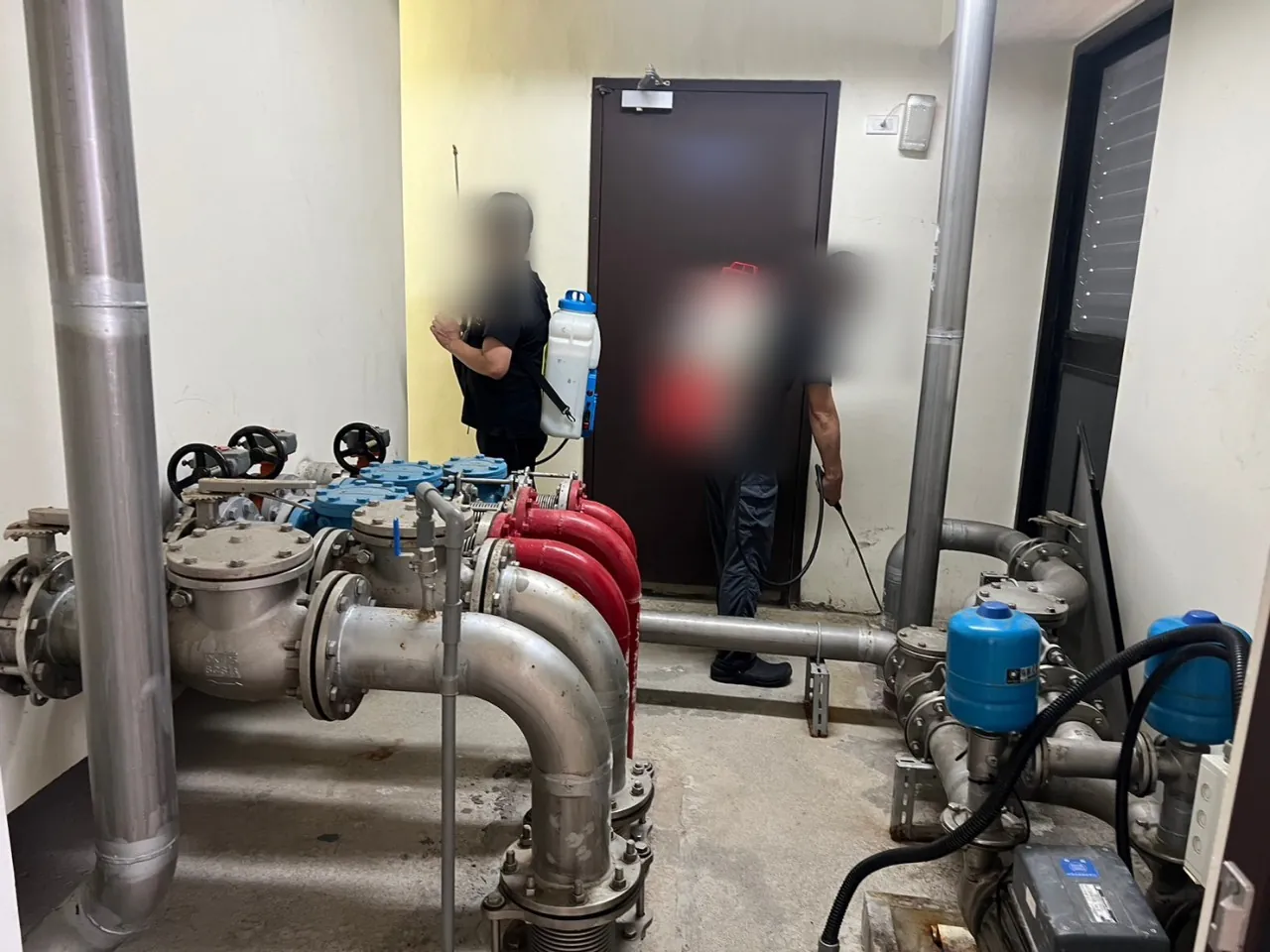 兩位技師在泵浦室沿設備周圍噴灑