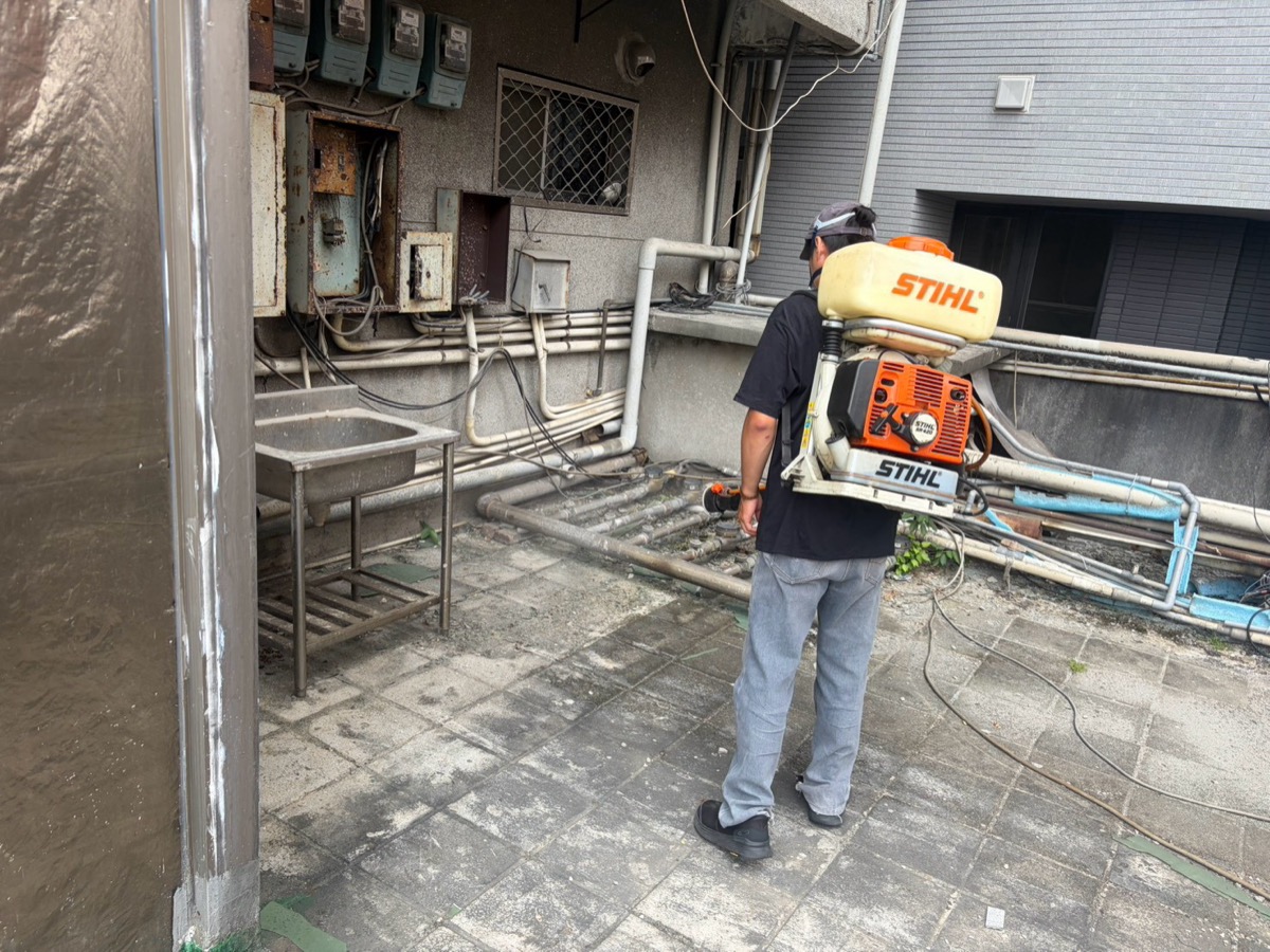 商業大樓外圍環境動力噴霧消毒施作,技師使用動力噴霧機處理管線與周邊區域